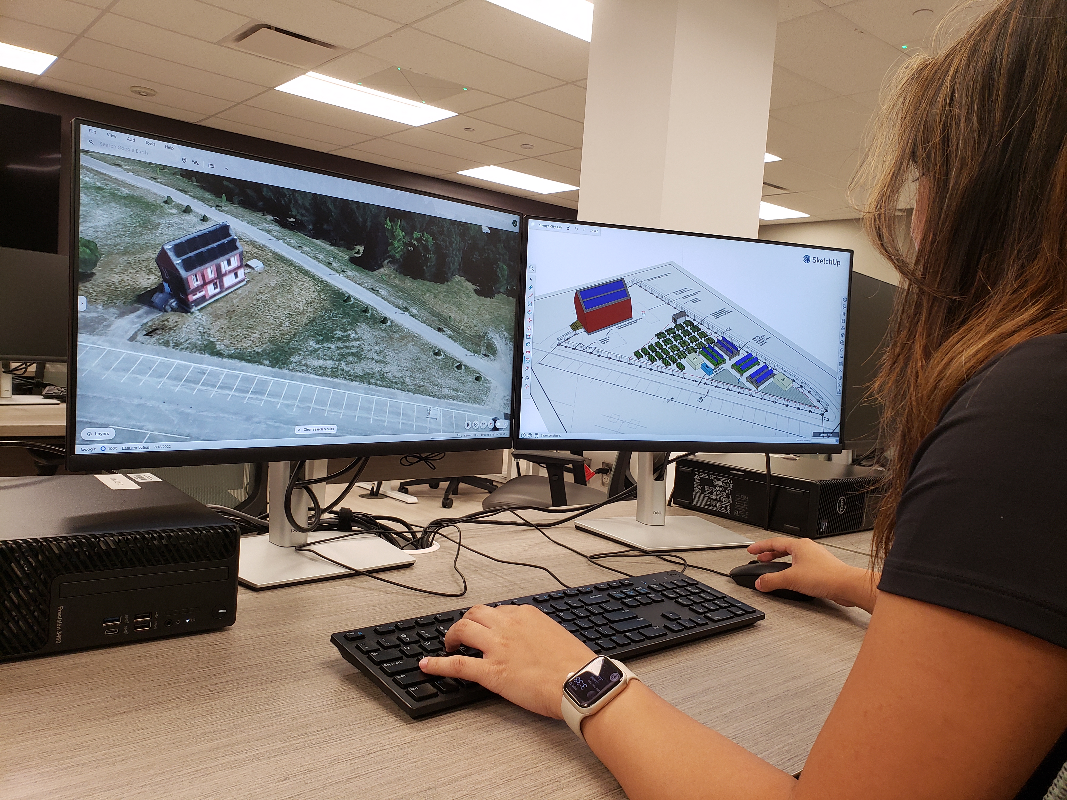 Jade intently works on a computer with two monitors, the left displaying the current unfinished Sponge City Lab Site and the right displaying a future render.